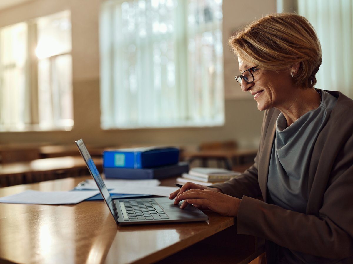 A teacher working on a laptop in a classroom